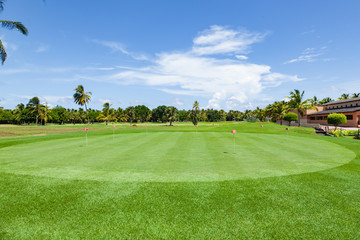 Obraz premium Panorama view of a golf course with installation green . Golf course with a rich green lawn in the countryside in summer day. beautiful scenery with a rich green turf and blue sky background 