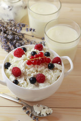 Composition with cottage cheese, fresh berries and yogurt on wooden table