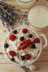 Composition with cottage cheese, fresh berries and yogurt on wooden table