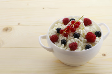 Bowl with cottage cheese and fresh berries on wooden table