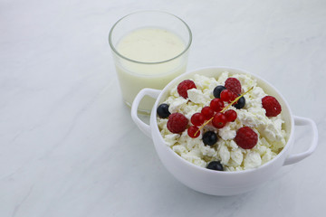 Bowl with cottage cheese and fresh berries on light background