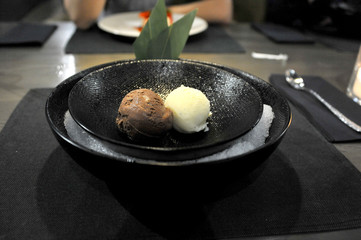 Ice cream in a black plate. Gourmet food in the restaurant. Healthy food. Close-up. Table setting