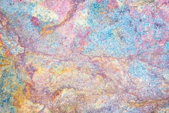 Colorful stone texture background. Big rock with colors of rainbow close up. Top view.