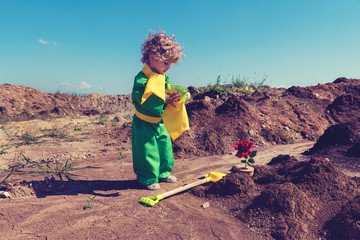 Cute toddler boy with curly blond hair holding green watering can Little prince concept Selective...