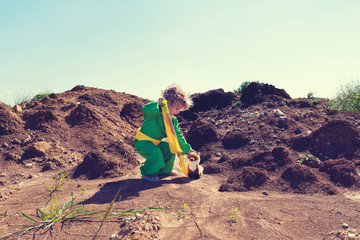 Cute toddler boy with plastic shovel and plush fox toy wearing green and yellow Selective focus