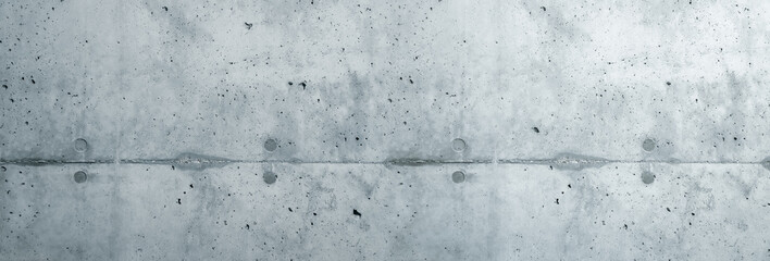 Gray concrete wall coarse facade made of natural cement with holes and imperfections separating layers as an empty rustic cold sterile texture wide large background empty space.