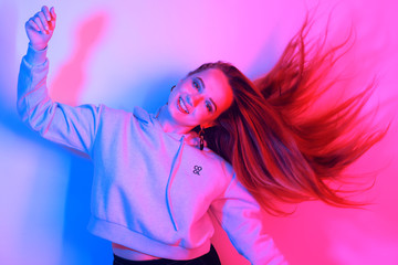 portrait of young elegant girl. Colored neon background, studio shot. Beautiful brunette woman. Hipster girl dancing in neon. Woman with stylish hair and red lips. Girl in a sweater and long hair.