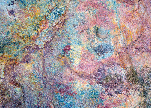 Colorful stone texture background. Big rock with colors of rainbow close up. Top view.