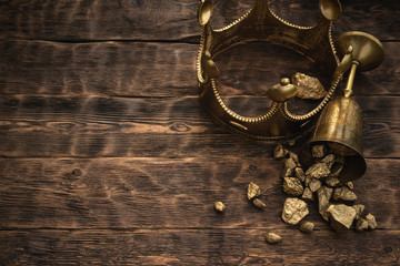 Golden crown and a award cup with a gold on a brown wooden table background with copy space.