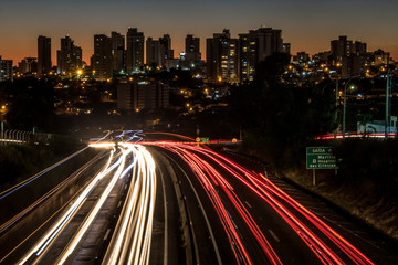 Marilia, Sao Paulo, Brazil, June 12, 2019. Trail of light caused by vehicular traffic in SP-294, Comandante Joao Ribeiro Barros Highway with buildings from downtown in the background, in Marília,