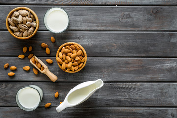 Almond milk in glass with almonds on wooden background top view copyspace