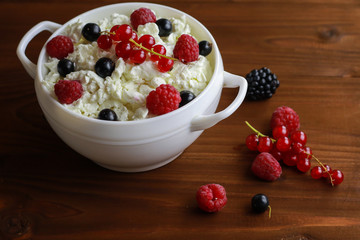 Bowl with cottage cheese and fresh berries on wooden table