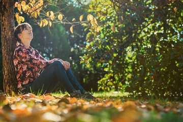 Young woman sitting under an autumn tree