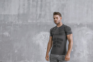 Muscular model in fashion sportswear on urban gray background. Portrait of brutal  strong guy with...