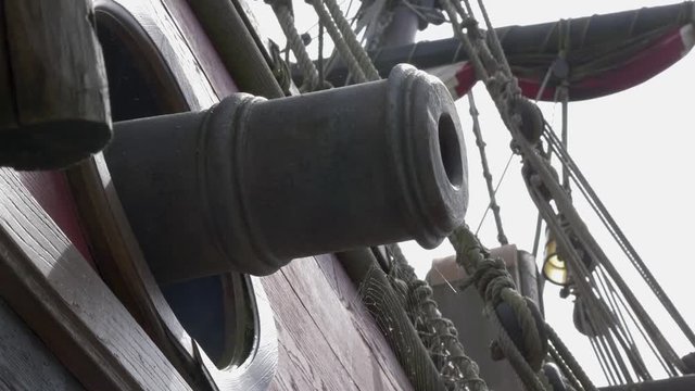 Bronze cannons, rope rigging and colourful sails on a naval sailing frigate show readiness for war from days gone by.