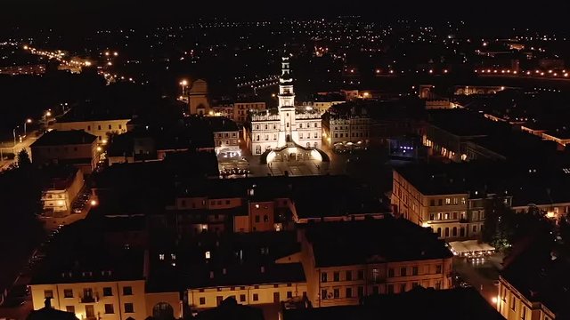 Zamosc, Lublin voivodeship. The city in Poland at night. The drone view. The drone is moving forwards focusing on the city hall. The beauty of the illuminated city.