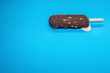 chocolate outer popsicle starts melting on blue background