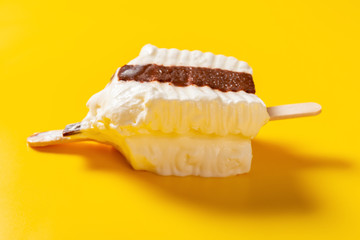 side view half eaten chocolate and milkshake flavor popsicle on a yellow background