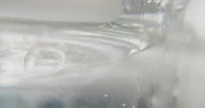 detail close up shot of a white viscous transparent liquid into which a drop falls. a transparent organic looking gel is floating ontop of it. art experimental footage