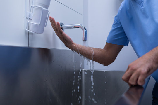 Male surgeon washing hands in sink at hospital