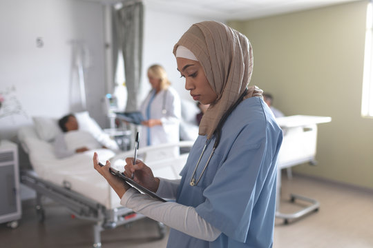 Doctor In Hijab Writing On Clipboard In Hospital