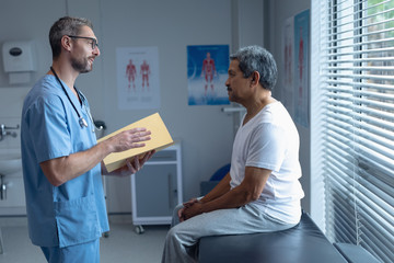 Male surgeon interacting with patient in hospital