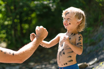 Happy father and son playing in the forest with mud