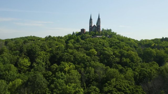 Holy Hill National Shrine of Mary, Wisconsin, USA, aerial view low level flight over tree tops drone footage.