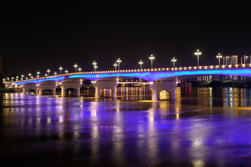 Fototapeta na wymiar Long exposure of Yongjiang bridge in Nanning city Guangxi province China at night. Double cantilever reinforced concrete and Double column pier bridge. Purple reflection on river. Perspective
