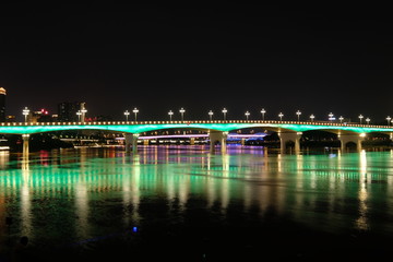Long exposure of bridge in Nanning city Guangxi province China at night. Double cantilever reinforced concrete and double column pier bridge. Green reflection on river