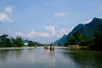Several bamboo rafts on peaceful river in Yangshuo Guilin China. Perspective green mountains. Blue sky with white clouds. Karst landform