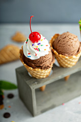 Chocolate ice cream in waffle cones with whipped cream and sprinkles