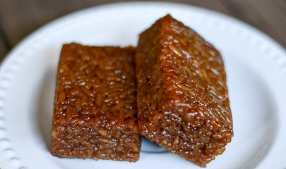 Wajik on wood background.  Wajik is traditional snack made with steamed glutinous (sticky) rice and further cooked in palm sugar, coconut milk, and pandan leaves.