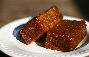 Wajik on wood background.  Wajik is traditional snack made with steamed glutinous (sticky) rice and further cooked in palm sugar, coconut milk, and pandan leaves.