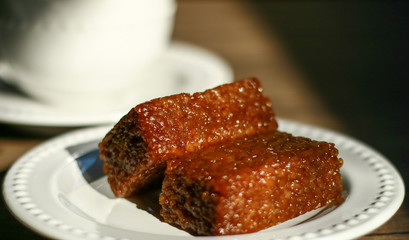 Wajik and a cup of tea on wood background.  Wajik is traditional snack made with steamed glutinous (sticky) rice and further cooked in palm sugar, coconut milk, and pandan leaves.