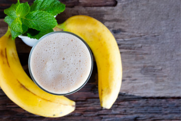 Banana smoothie white fruit juice milkshake blend beverage healthy high protein the taste yummy In glass drink episode morning on a wooden background  from top view.