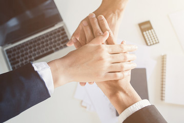 A group of businessmen shake hands with each other in the background of their desks and cheer on their business partners.