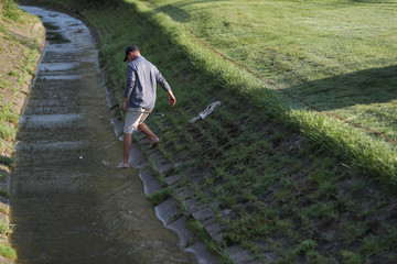 A tournament golfer, after hitting his tee shot into a creek, hits it out of a creek, to avoid a penalty stroke © Ron Alvey