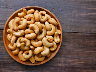 Cashew nuts in a bowl placed on a wooden background