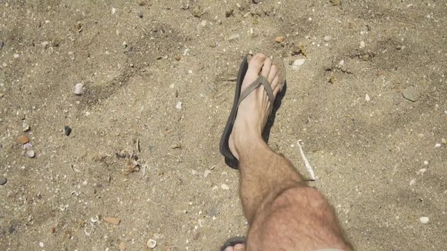 Male wearing Flip Flops walking in the dry sand on the Beach at Cala de Mijas on the Costa Del Sol in Southern Spain.