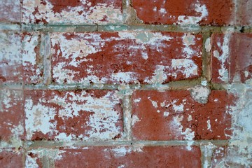 Rough unpainted and stained red brick wall in macro with white paper remains