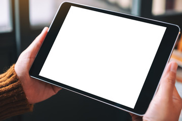 Mockup image of a woman sitting and holding black tablet pc with blank white desktop screen