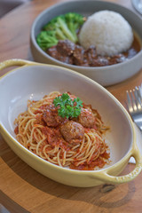 Spaghetti meatballs with tomato sauce in yellow bowl.