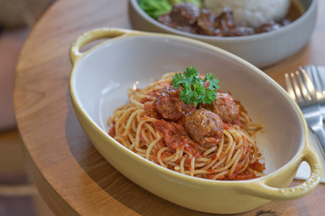 Spaghetti meatballs with tomato sauce in yellow bowl.
