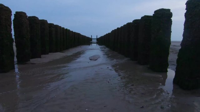 4K slowmo shot between several pole heads on the beach of Zoutelande, Groot Valkenisse, Zeeland, Netherlands