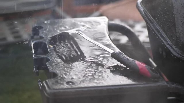 Rain falling on a metal spatula during a rain storm on a black barbecue grill, in 60 frames per second  4k.