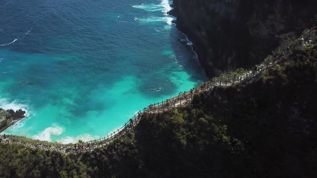 Dramatic Drone Shot flying over the ridge, panning down and revealing the beautiful KelingKing Beach. Sunny, clear day on the island of Nusa Penida, Indonesia.