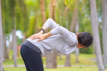 Young woman with lower back pain while running exercising after jogging in park