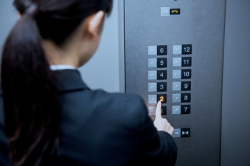 エレベーターのボタンを押す女性 © UTS