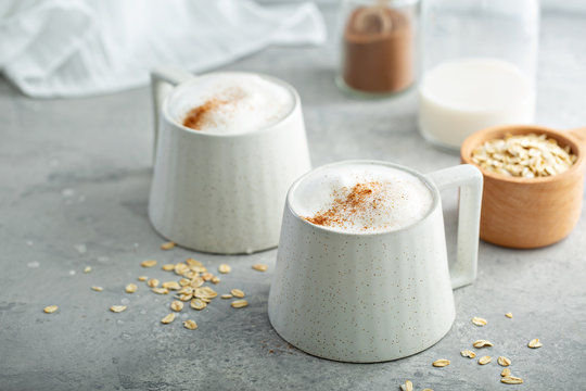 Oat milk latte with thick foam in ceramic mugs topped with cinnamon